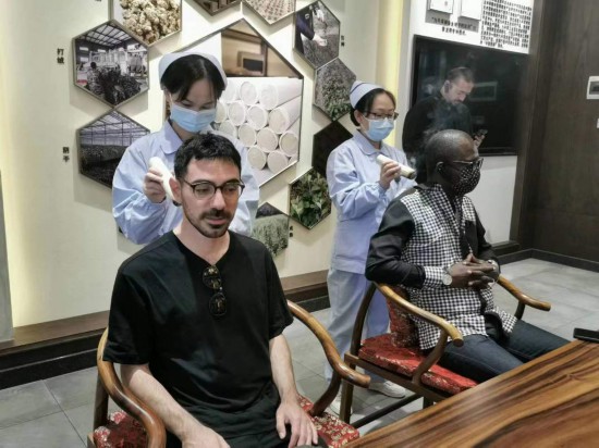 2023“一帶一路”媒體合作論壇聯(lián)合采訪團團員在九牛草展示館體驗艾灸。（本報記者 黃超攝）