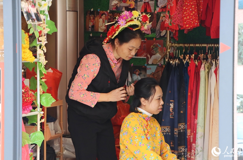 泉州府文廟附近，一名店主正為過(guò)路游客梳理頭發(fā)以佩戴“簪花圍”。人民網(wǎng) 黃東儀攝