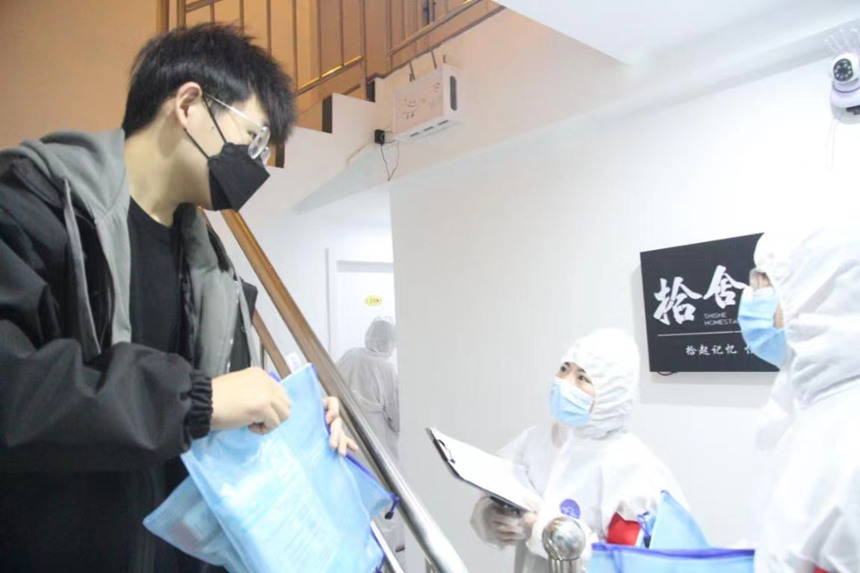 社區(qū)工作人員和志愿者身穿防護(hù)服上門(mén)送馬應(yīng)龍大健康防疫包。徐帥攝