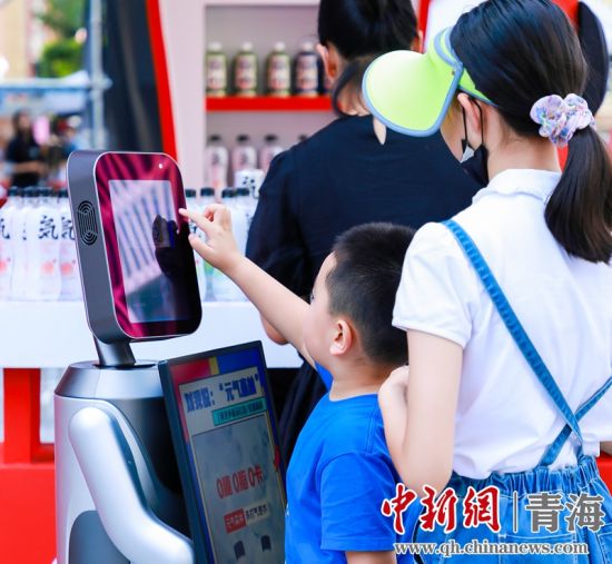 圖為一名小朋友正在和機(jī)器人“志愿者”進(jìn)行互動(dòng)。 沐聞 攝
