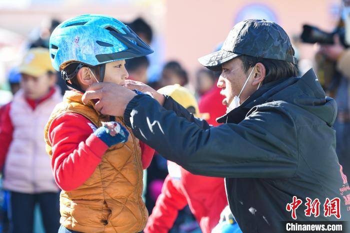 圖為拉薩市實(shí)驗(yàn)幼兒園孩子在教練的幫助下穿戴頭盔。　何蓬磊 攝