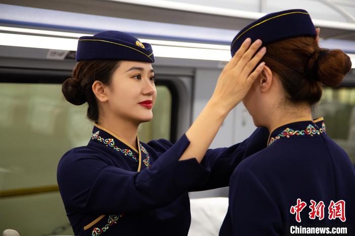 圖為青藏鐵路西格段“復(fù)興號(hào)”動(dòng)車組乘務(wù)員互相整理新制服?！±罾?攝