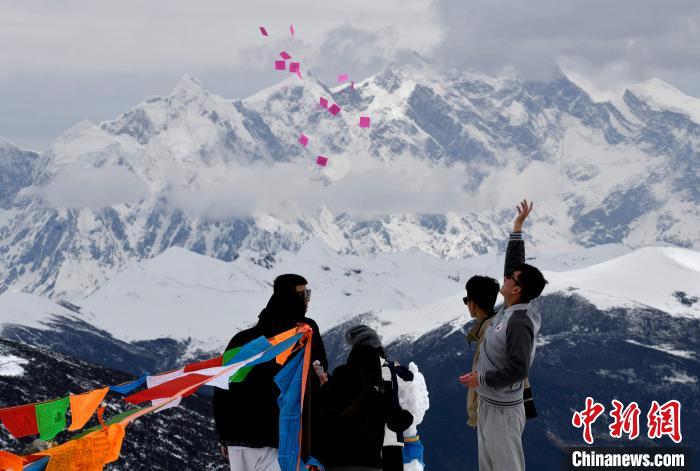 圖為5月14日，游客在西藏林芝色季拉山觀景臺拋灑“隆達”(風馬旗，藏族民眾的一種祈福方式)?！±盍?攝