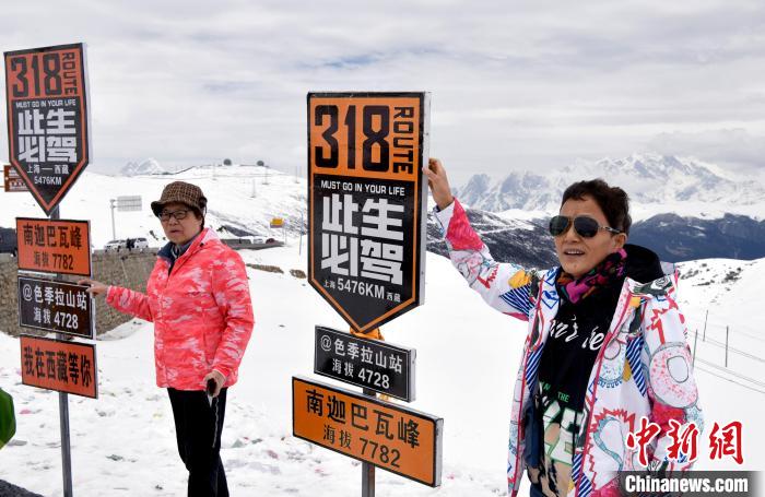 圖為5月14日，西藏林芝色季拉山觀景臺，游客與南迦巴瓦峰合影。　李林 攝